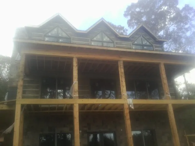 Dormers and porch framing on a large log home under construction — Roof Coating work by our crew in Steinauer