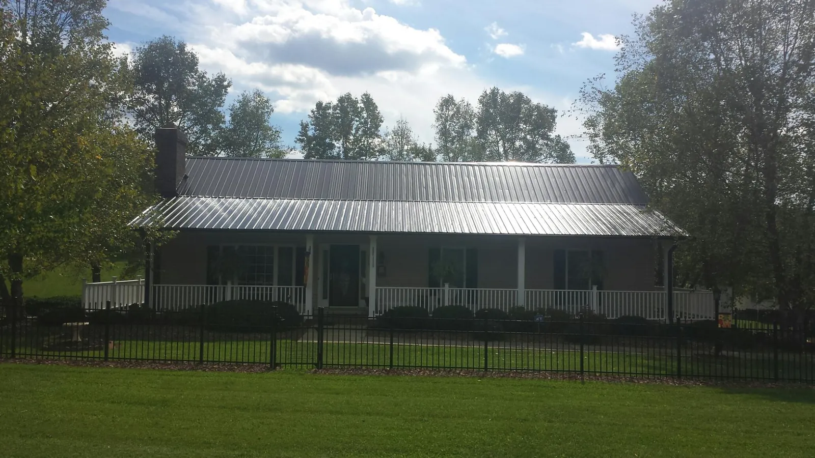 Gray metal roof on a brick ranch with a full width front porch — Gutter Guard Installation work by our crew in Steinauer