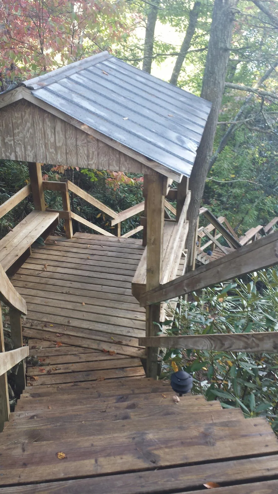 Metal roofed shelter over wooden steps on a wooded walkway — Skylight Repair & Installation work by our crew in Steinauer