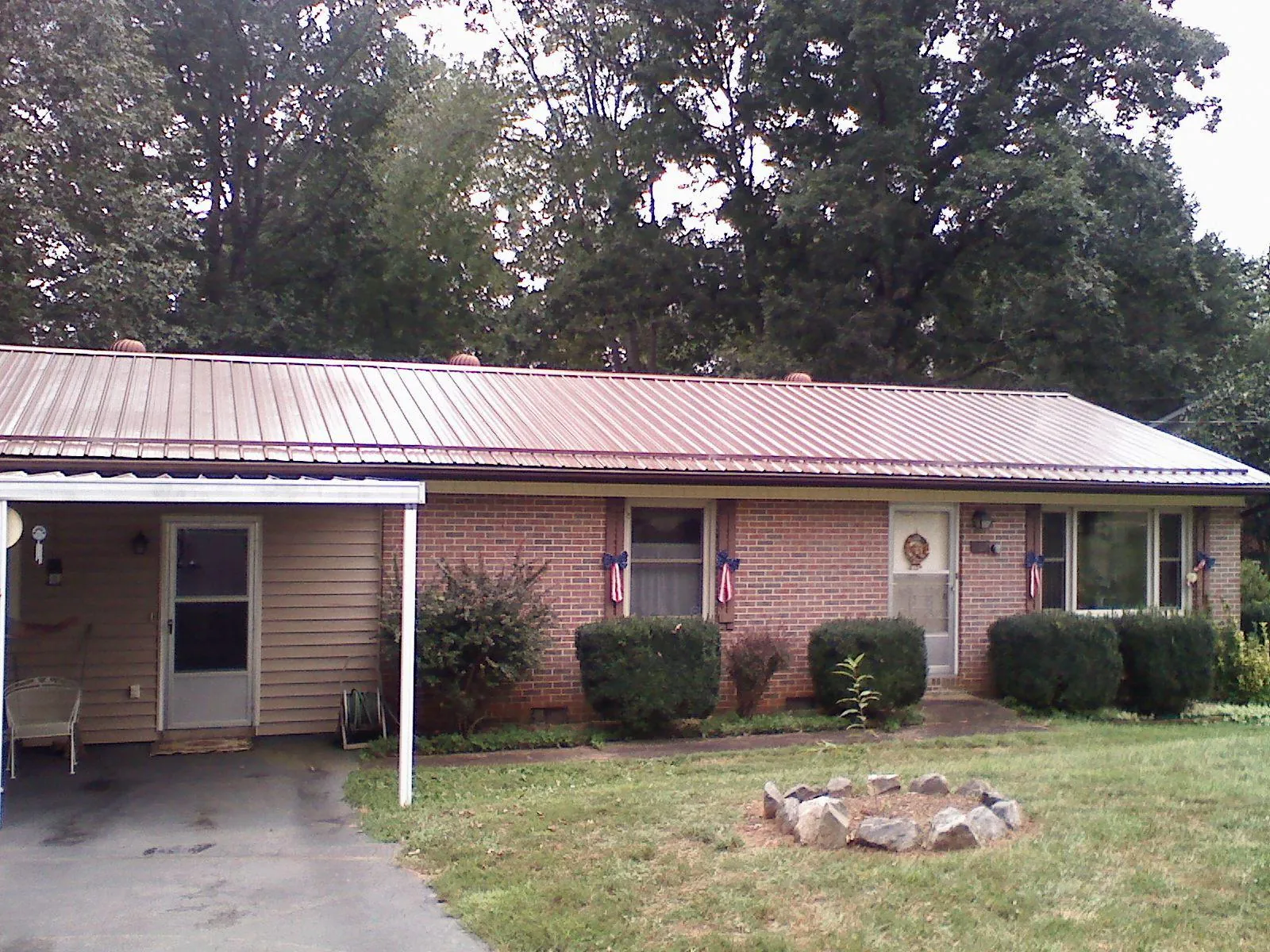 Bronze metal roof and carport on a brick ranch home — Roof Repair work by our crew in Steinauer